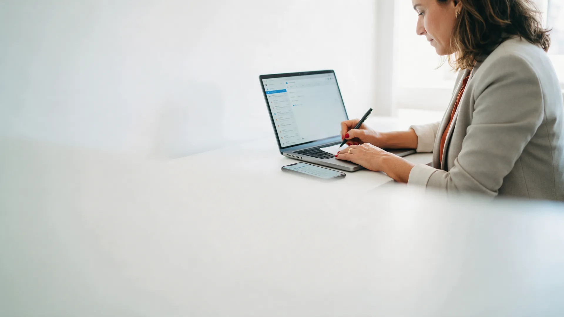 Profissional escrevendo um e-mail de trabalho no notebook, com a mesma caixa de entrada no celular